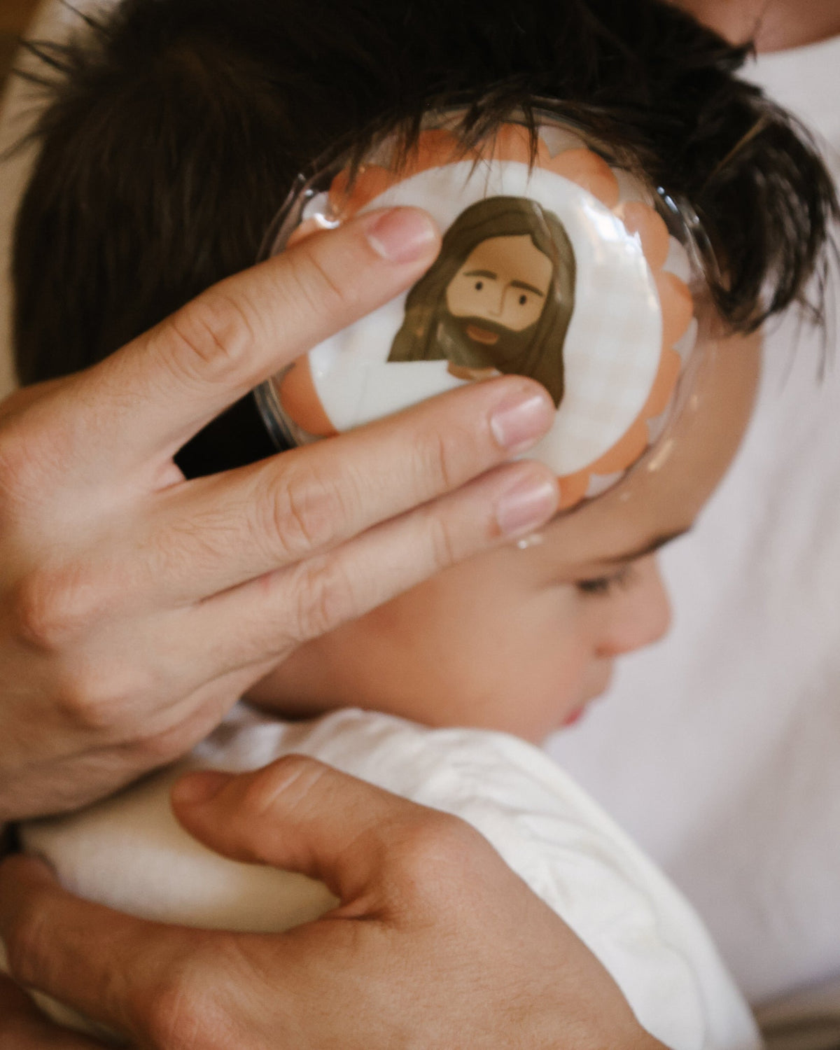 Parent holding a Jesus Heals hot and cold pack on a child's head to soothe a bump